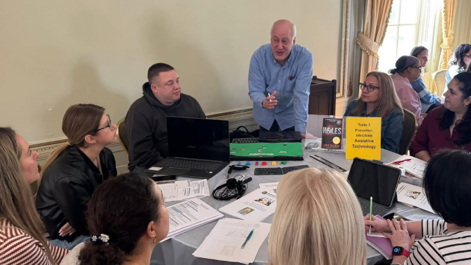 A picture of three people in front of a room with other people listening to a lecture.